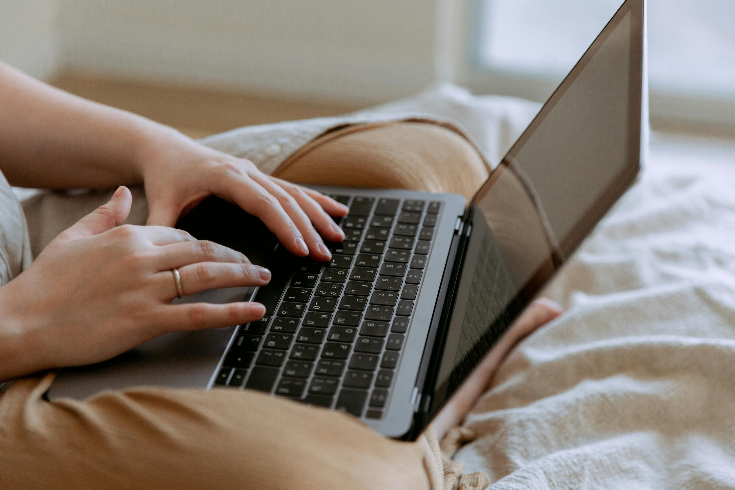 Hands typing on a laptop at home